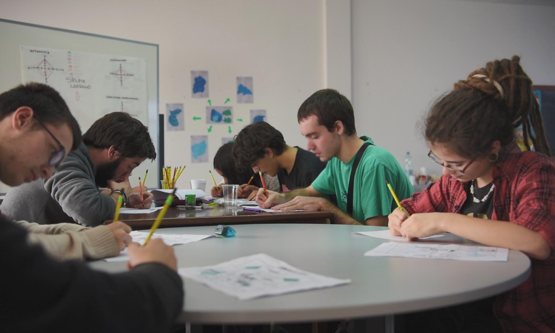 Jóvenes escribiendo alrededor de una mesa