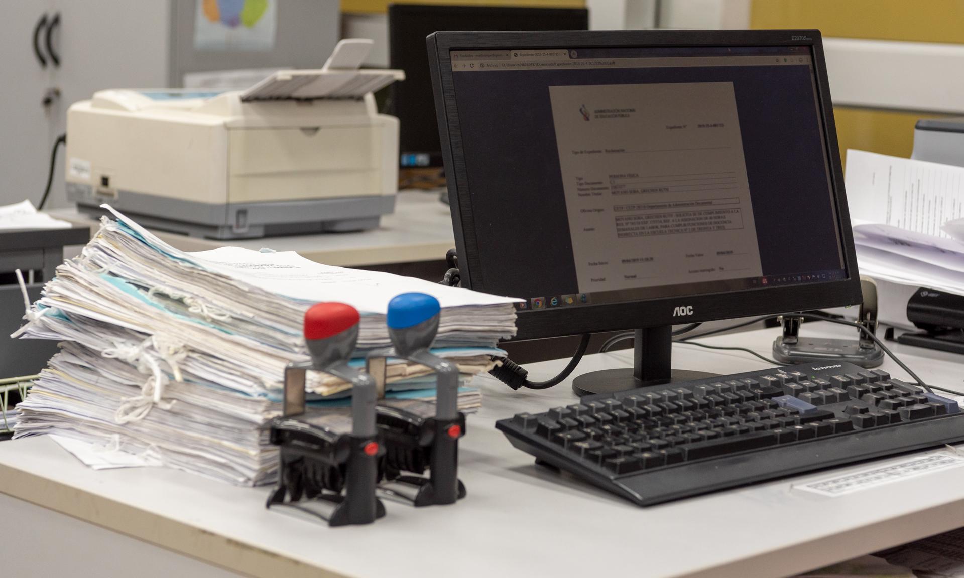 Escritorio de trabajo con expedientes físicos y electrónicos