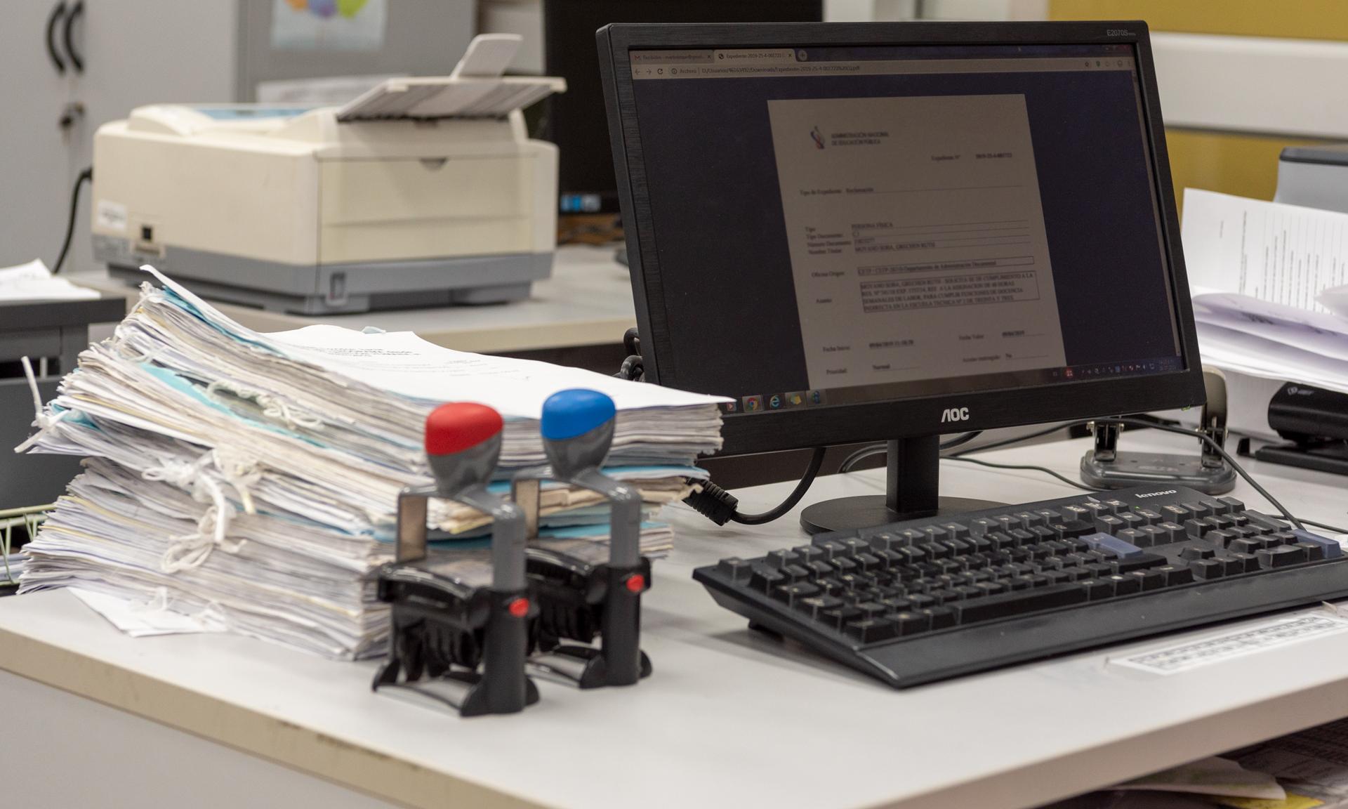Escritorio de trabajo con expedientes, computadora y elementos de oficina