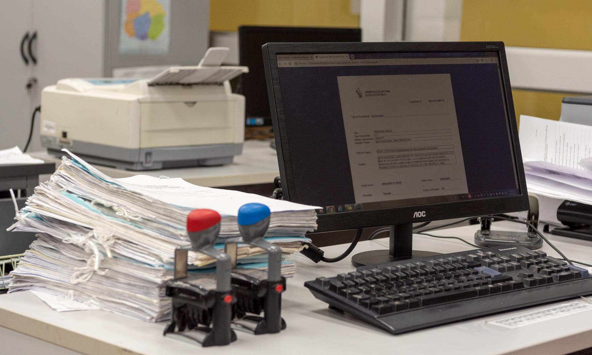 Escritorio de trabajo con expedientes, computadora y elementos de oficina