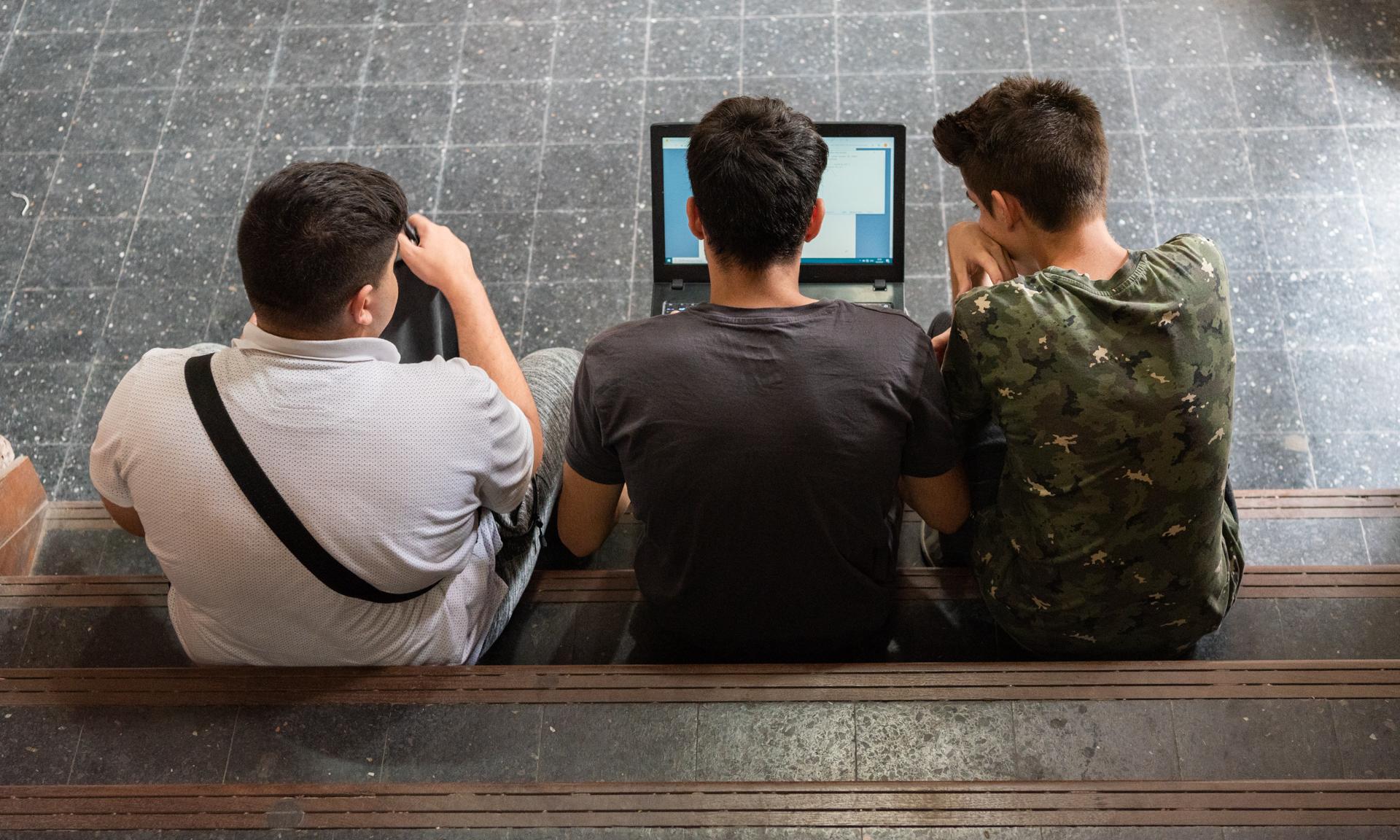 Jóvenes agrupados alrededor de una computadora portátil. 