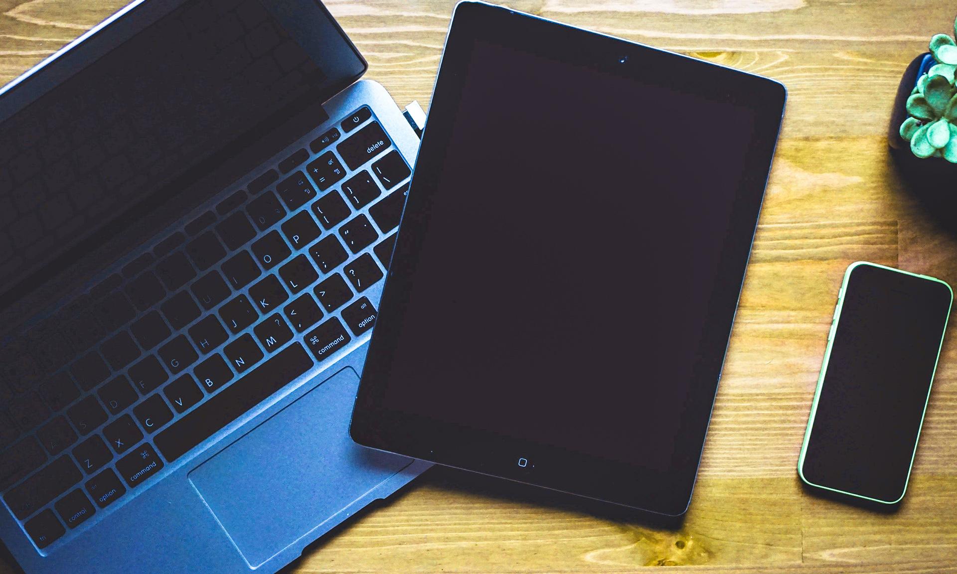 Computadora portátil, tableta y teléfono móvil inteligente sobre una mesa.