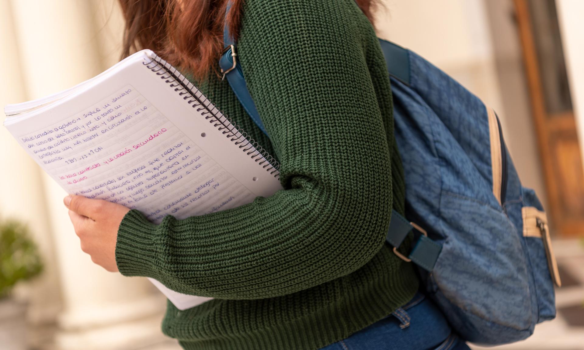 Estudiante con una mochila y una cuadernola en su brazo