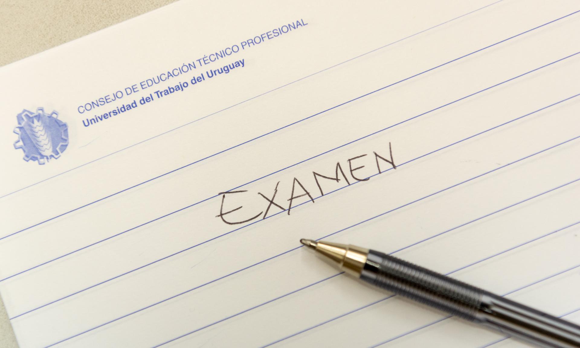 Una lapicera sobre una hoja de exámenes del CETP con la palabra EXAMEN escrita