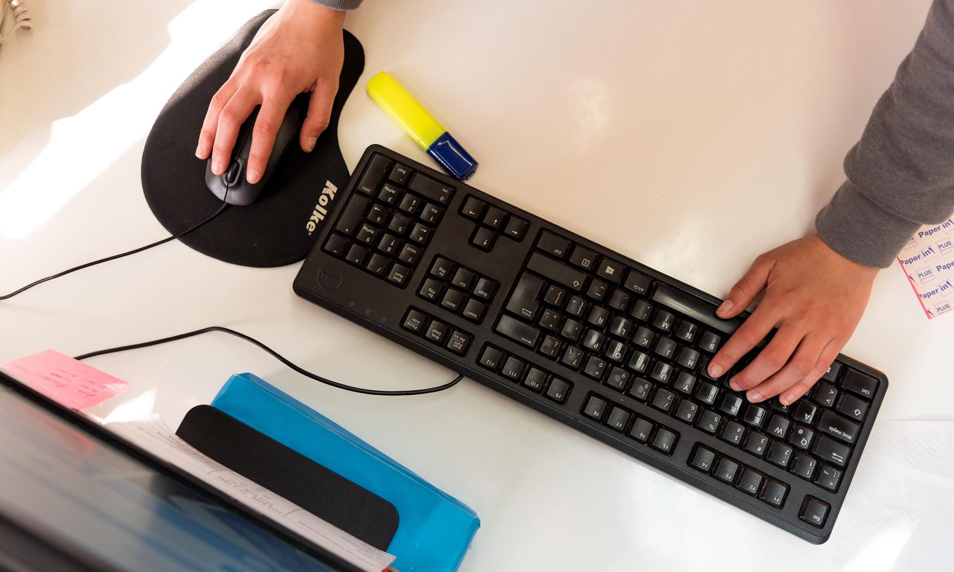 Persona manipulando periféricos de computadora en lugar de trabajo