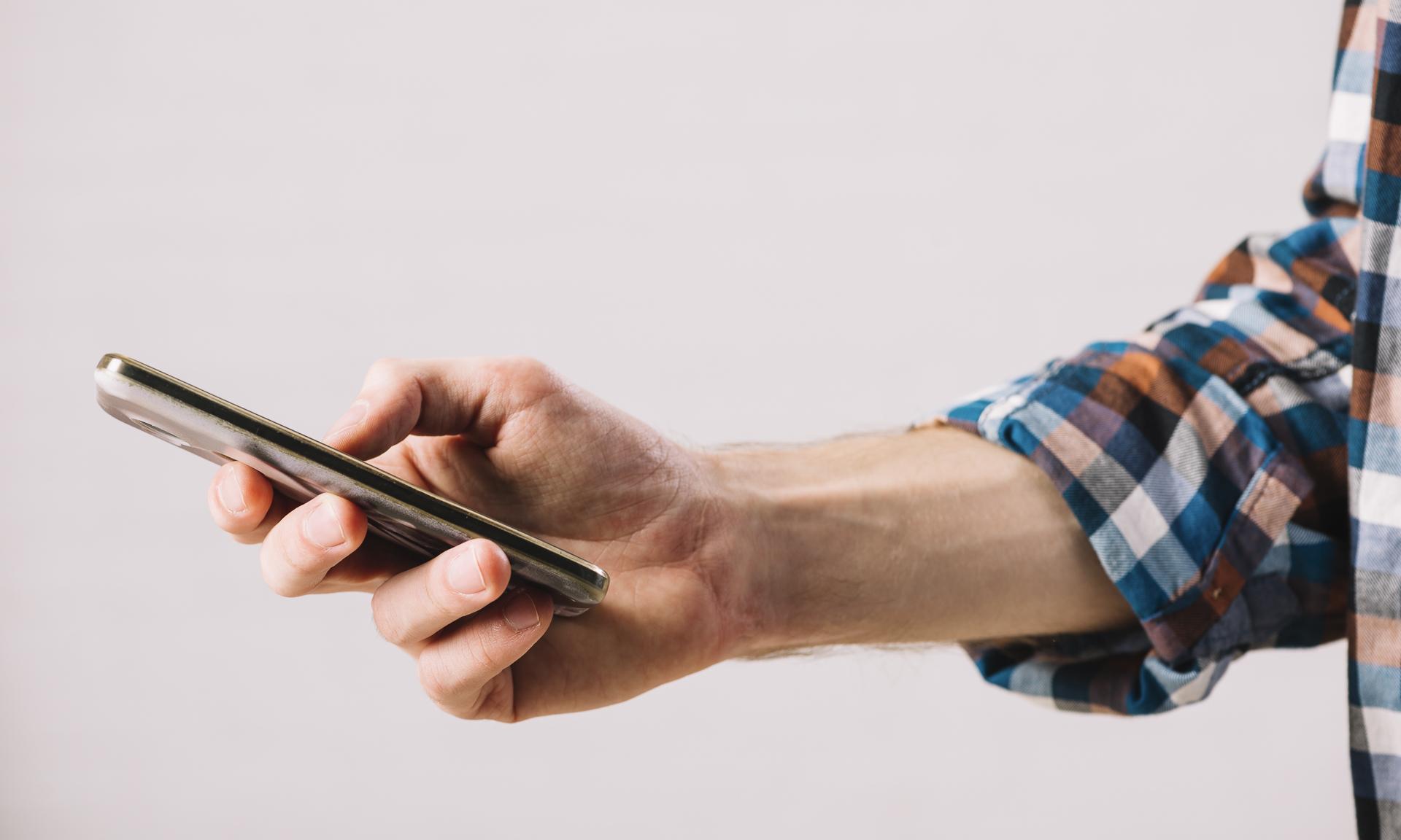 Mano de joven sobre celular en el que escribe