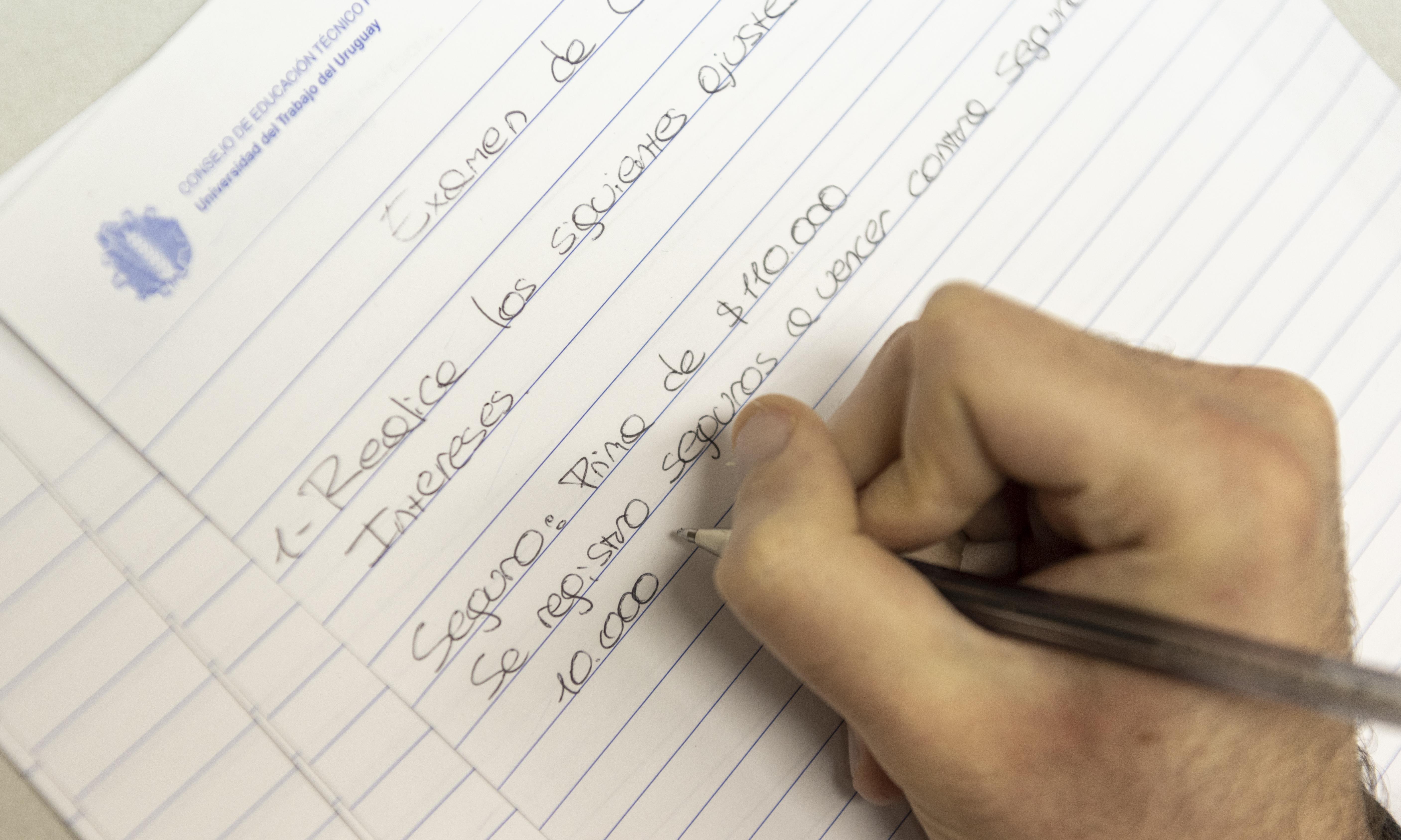 Mano escribiendo con un bolígrafo durante un examen.