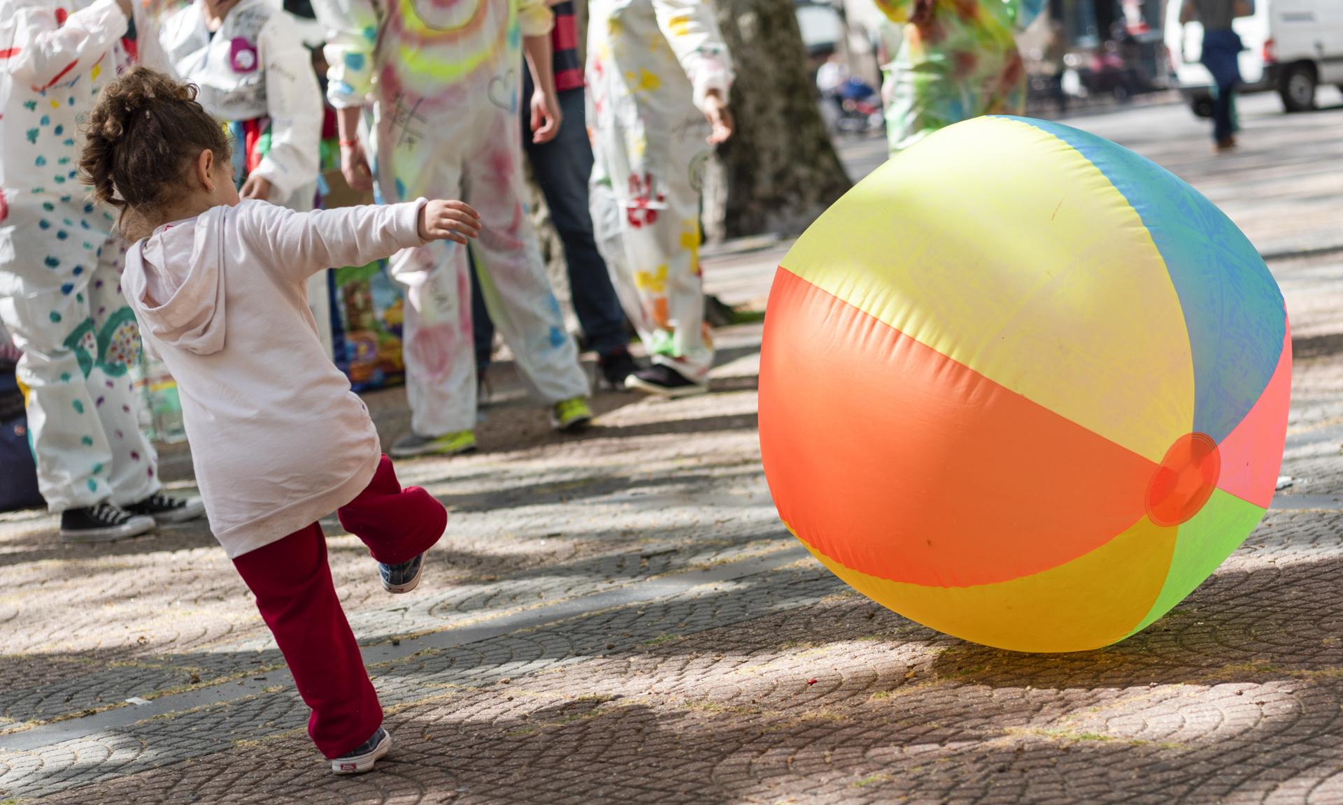 Niña jugando con una pelota inflable al aire libre.